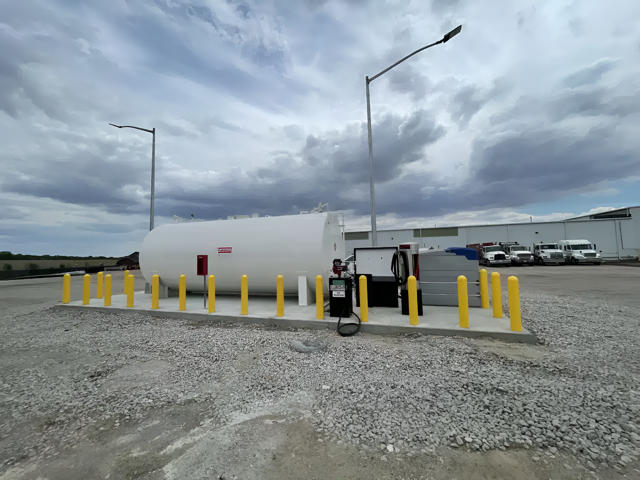 White Flameshield® tank installed in a gravel lot with yellow bollards for fuel storage.