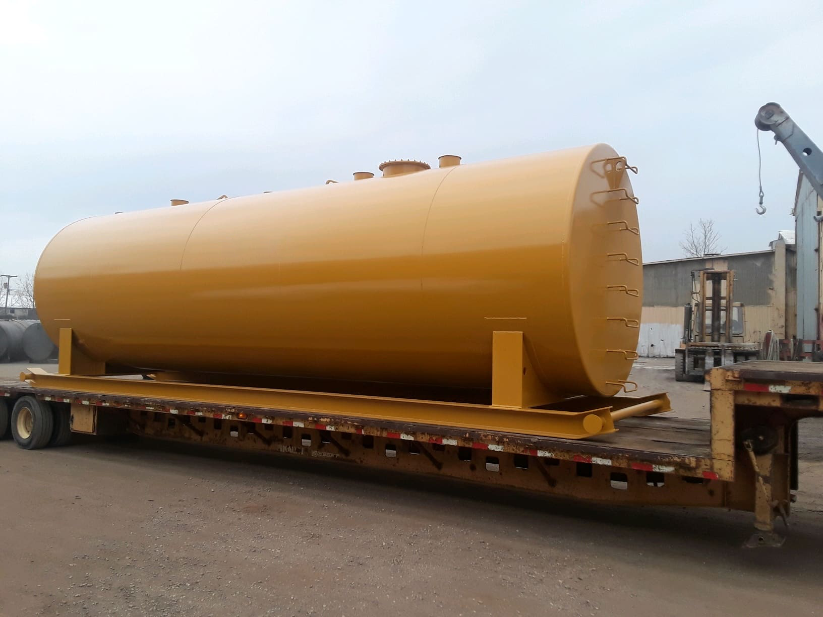 Yellow industrial fuel storage tank securely mounted on a flatbed trailer, designed for high-capacity fuel storage and transportation.