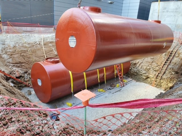 Double-wall underground steel storage tanks positioned in a construction site for installation.