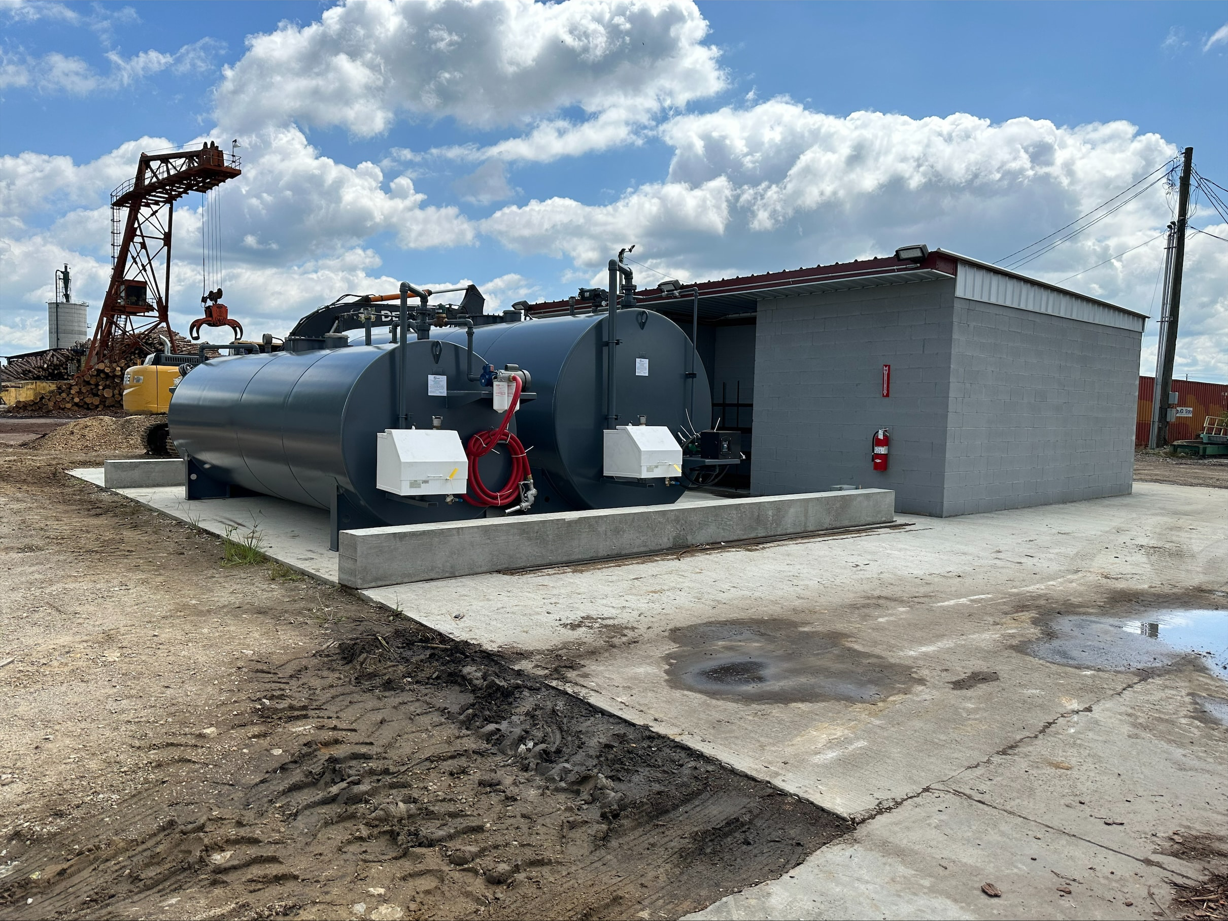 Black industrial fuel storage tanks installed next to a concrete building, used for safe and efficient fuel storage in a commercial facility.