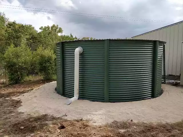 corrugated tank with green paint installed in a back yard
