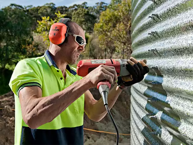 Man installing bolts on a corrugated steel tank