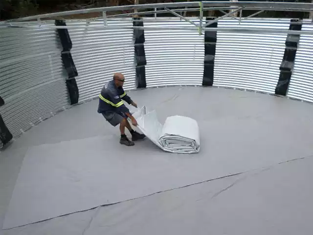Man unrolling and installing a liner in a corrugated tank