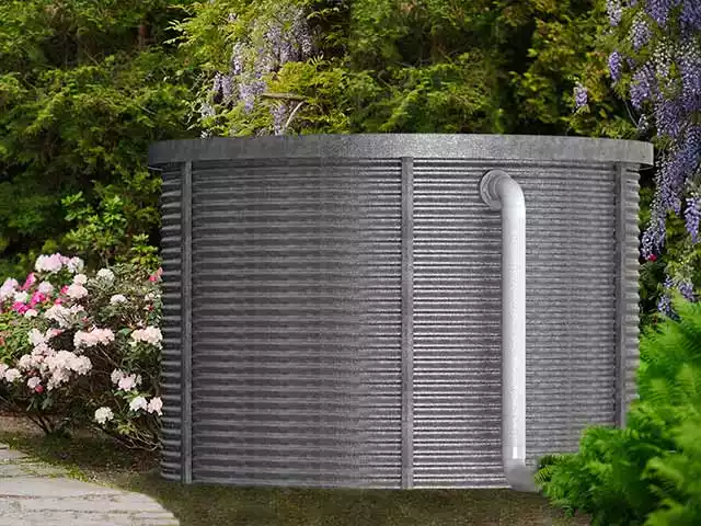 5000-gallon corrugated steel water tank in a garden setting