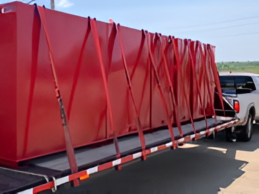 Large red aboveground oil storage tank securely fastened on a trailer for transport, suitable for bulk storage in agricultural or industrial operations.