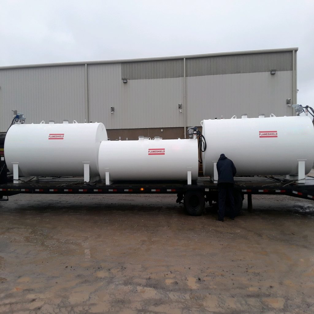 Three white Flameshield® tanks on a flatbed truck, ready for transportation.