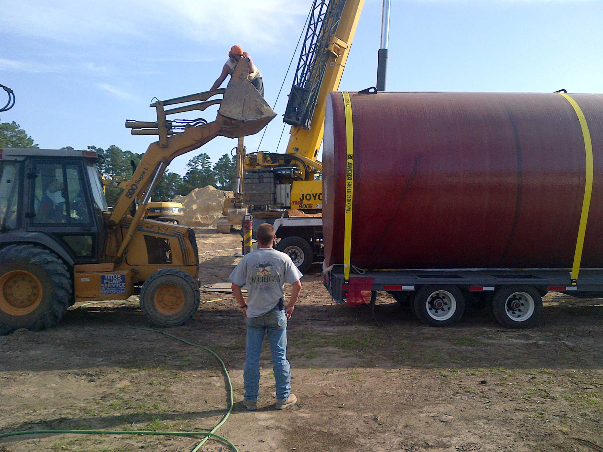 Transportation and setup of a large underground storage tank at an industrial site, ready for installation to ensure safe fuel storage.