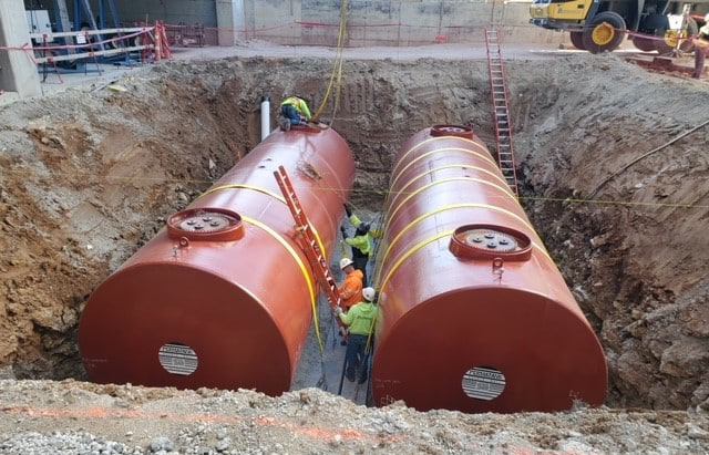 Double-walled underground storage tanks being installed at a commercial construction site, designed for maximum protection of stored fuels.