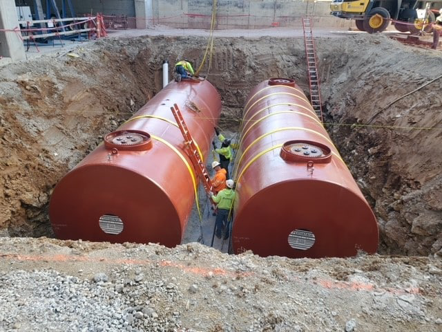 Double-walled underground storage tanks being installed at a commercial construction site, designed for maximum protection of stored fuels.