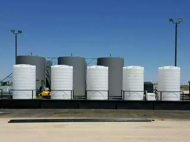 Vertical storage tanks of varying sizes standing upright nin a line next to each other