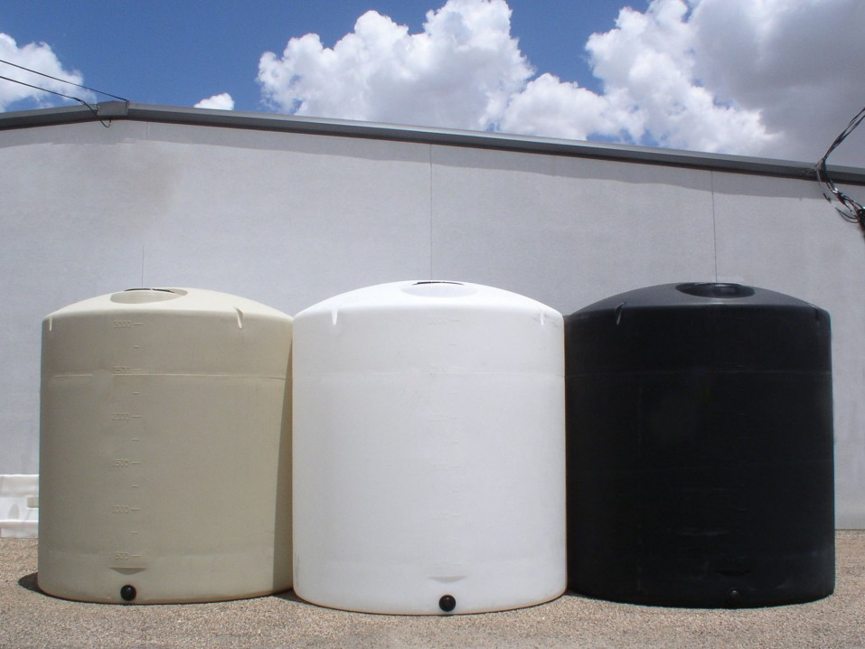 Three polyethylene water storage tanks in beige, white, and black, standing side by side outdoors