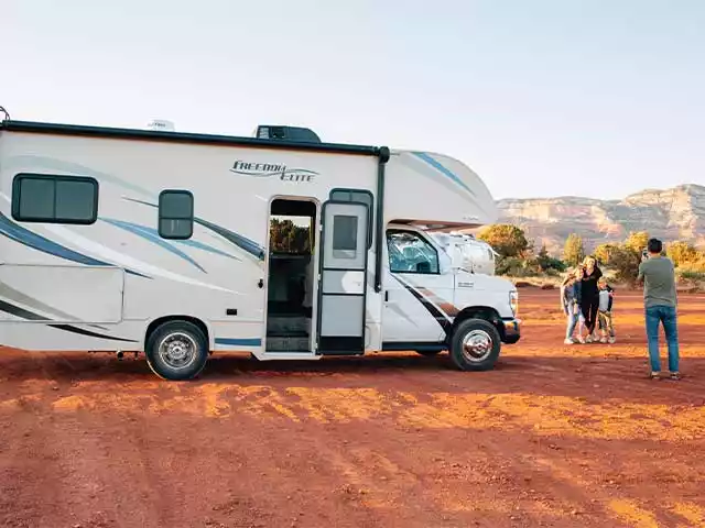 man taking a photo of his family next to an rv
